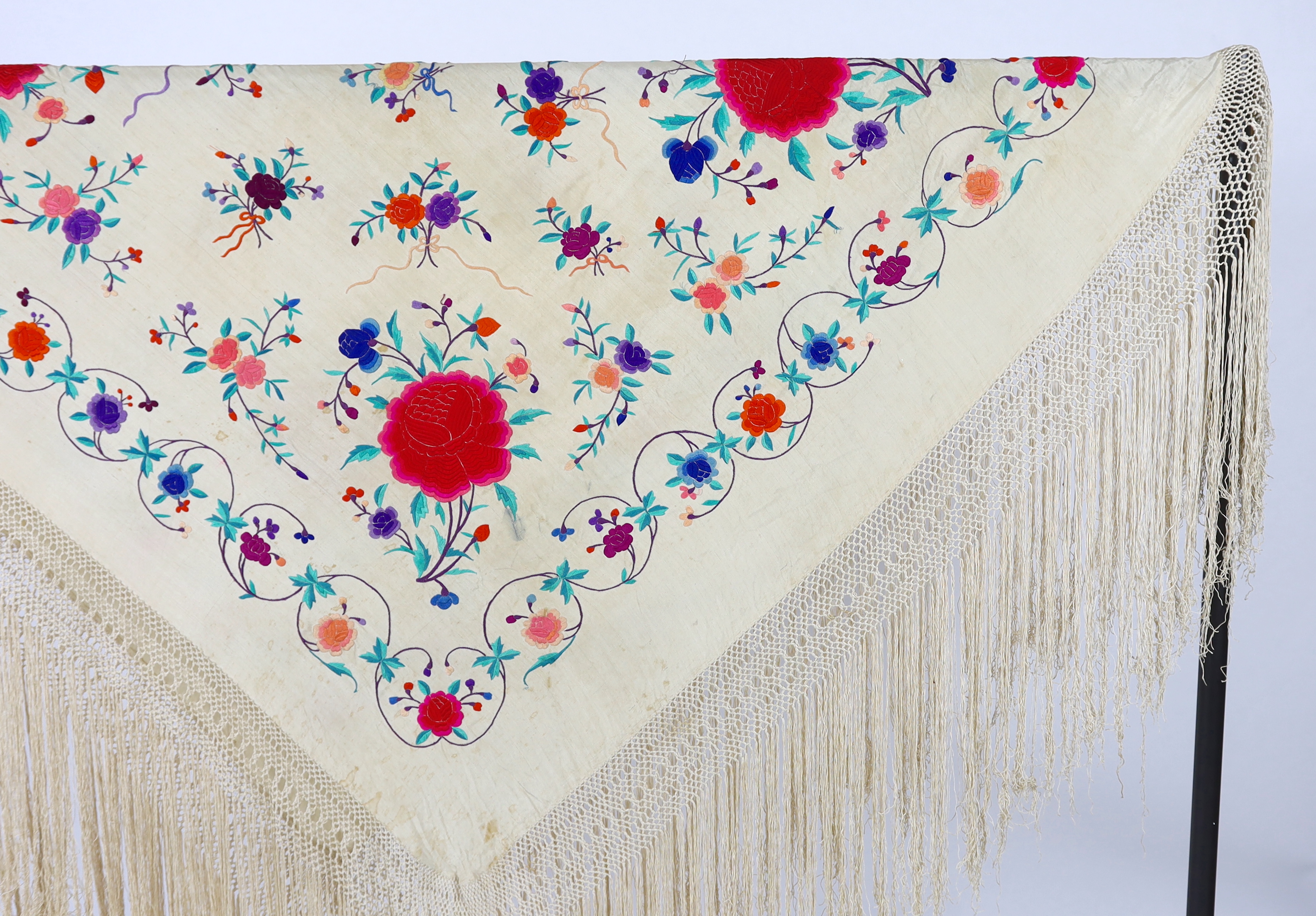 A late 19th / early 20th century cream silk fringed shawl, embroidered with all over polychrome silk floral motifs, 130 x 150cm not including fringe